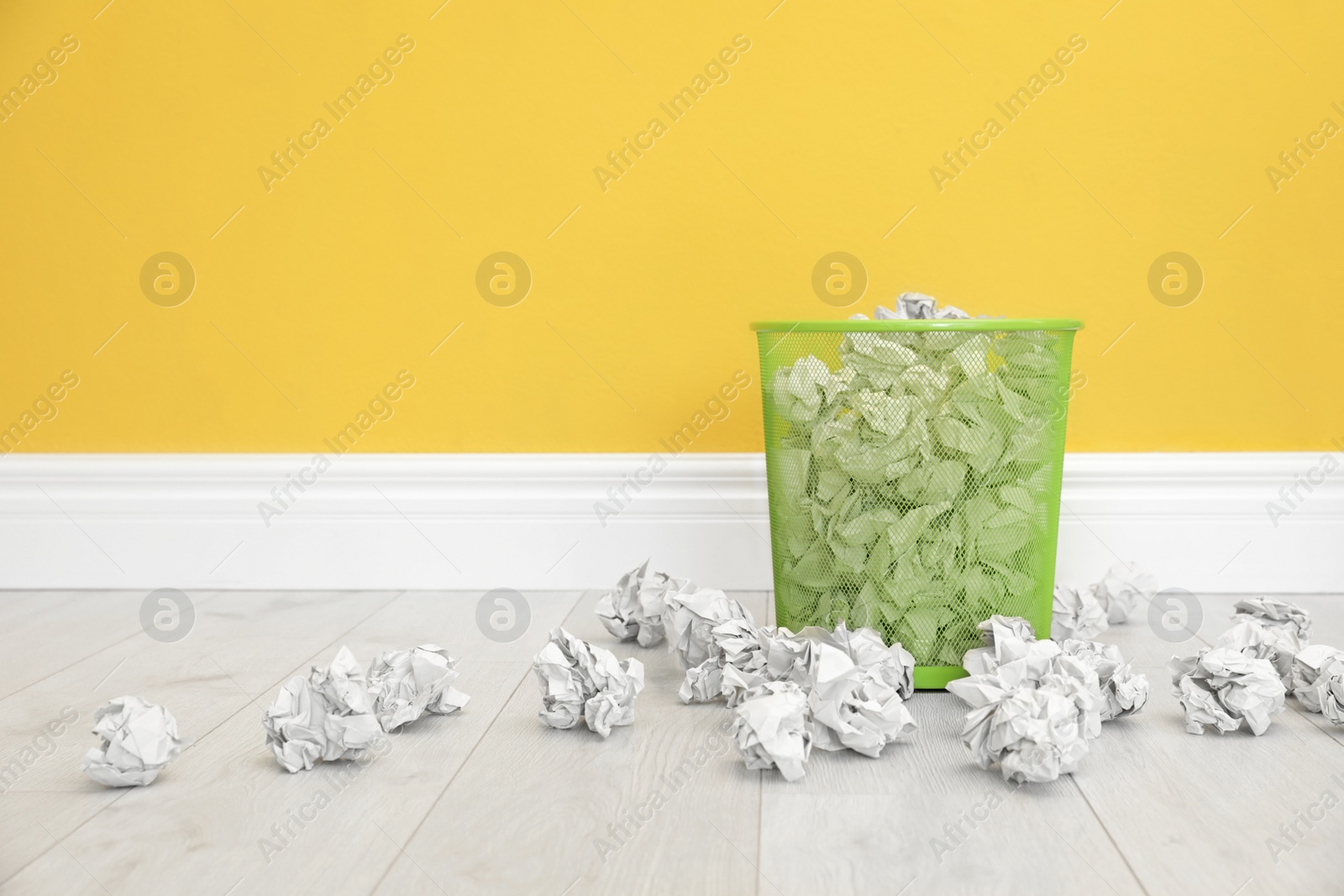 Photo of Metal bin with crumpled paper against color wall, space for text