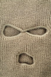 Beige knitted balaclava as background, closeup view
