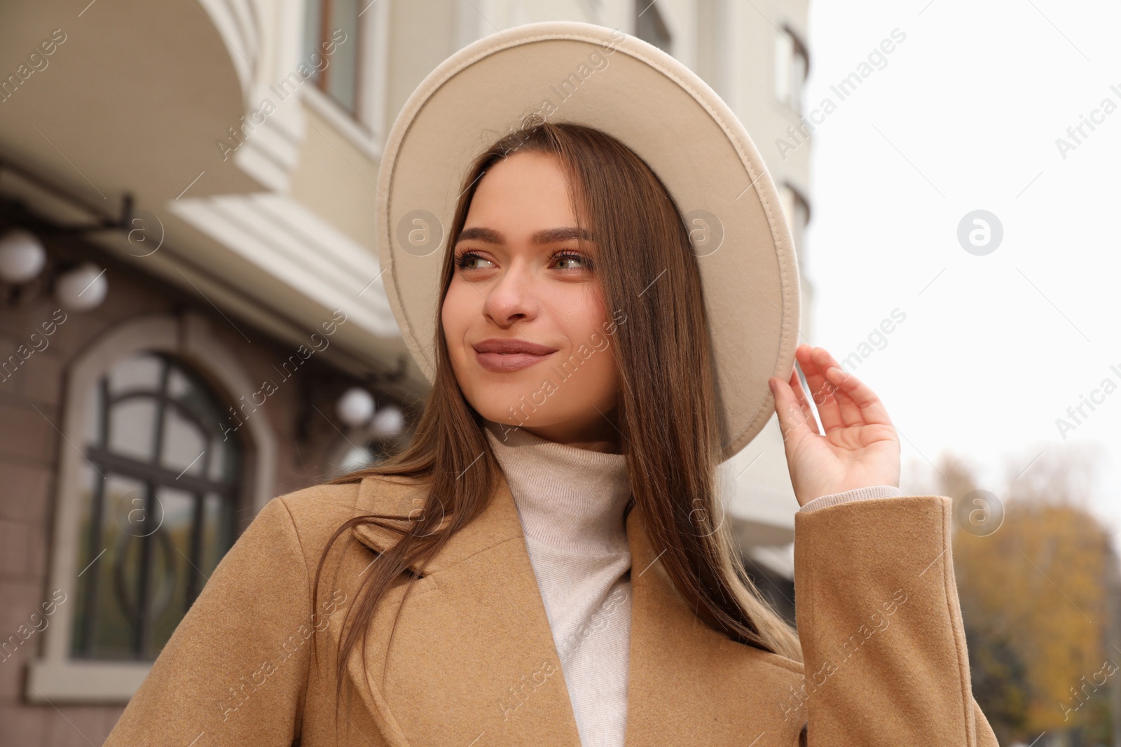Photo of Beautiful young woman wearing stylish autumn clothes on city street