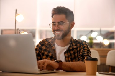 Man working with laptop at table in cafe