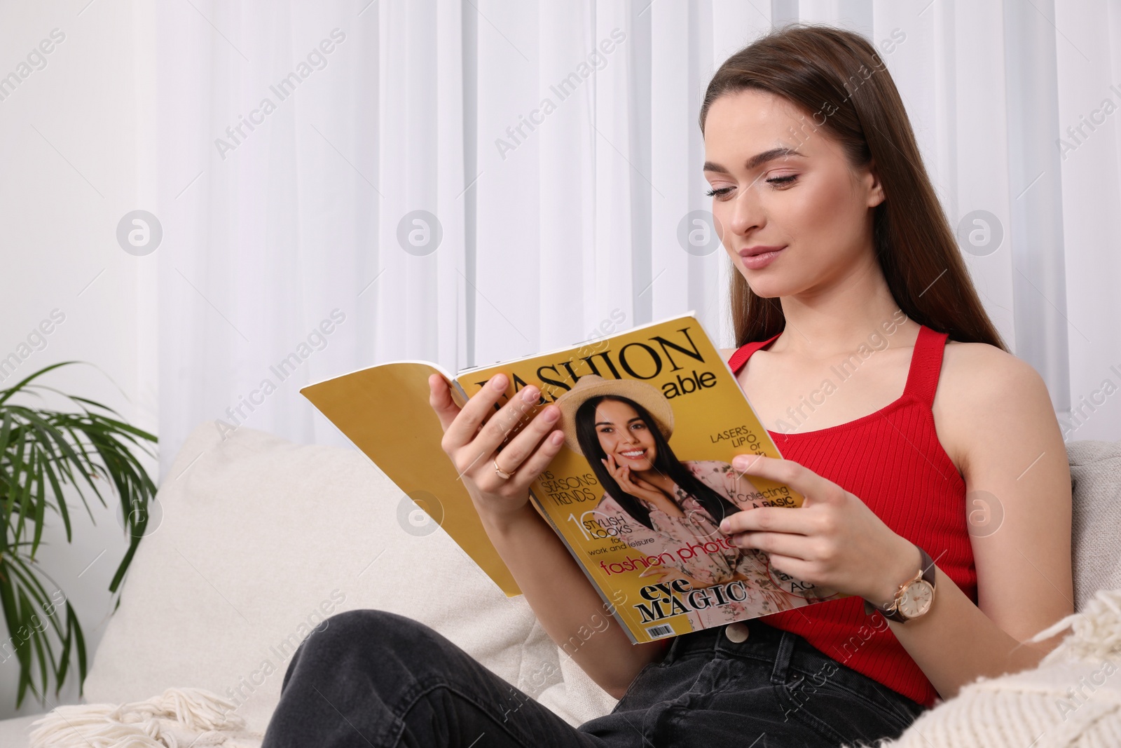 Photo of Young woman reading fashion magazine at home