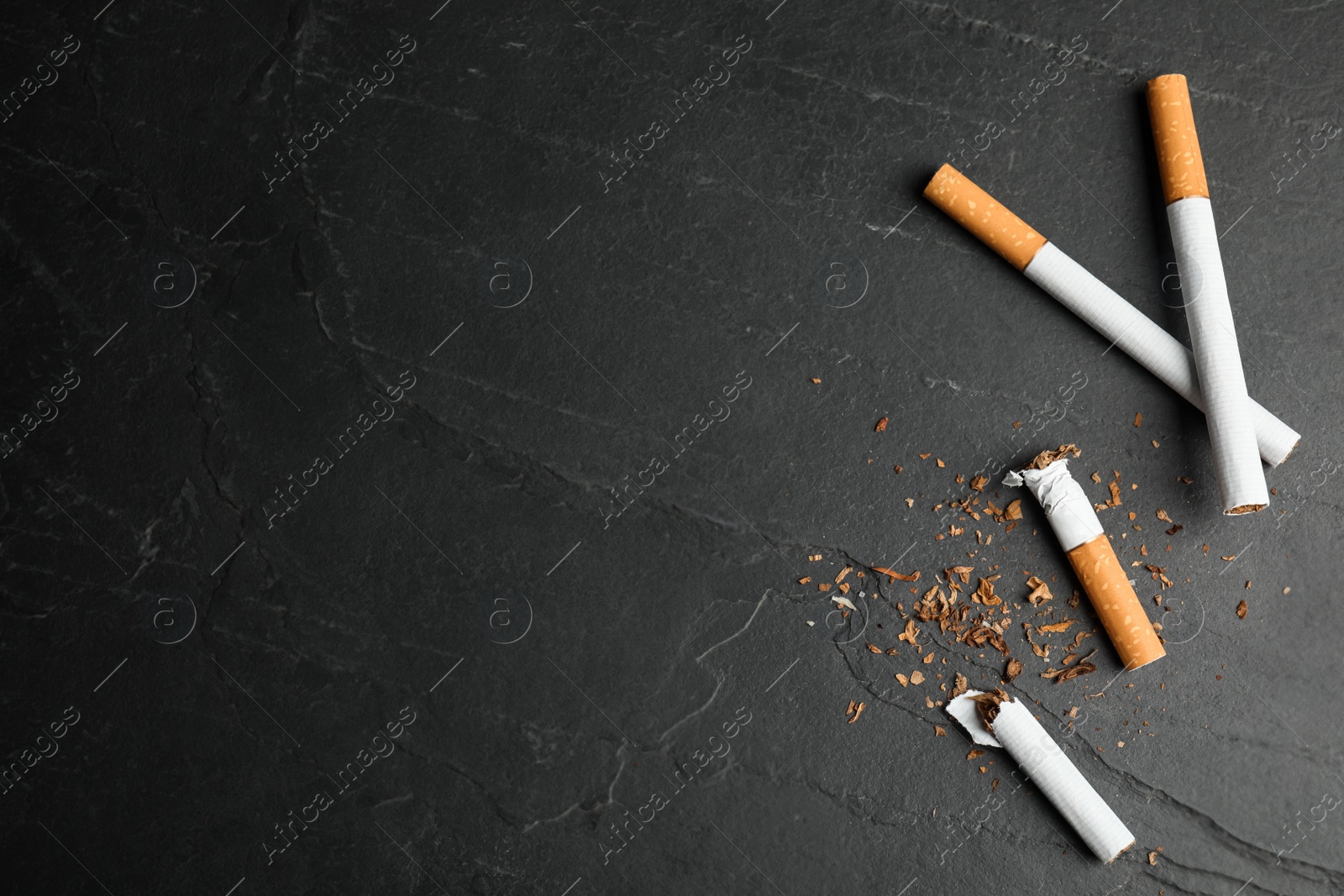 Photo of Broken and whole cigarettes on black table, flat lay with space for text. Quitting smoking concept