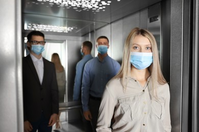 Photo of Group of people with face masks in elevator. Protective measure