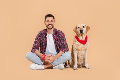 Photo of Happy man with his cute Labrador Retriever on beige background