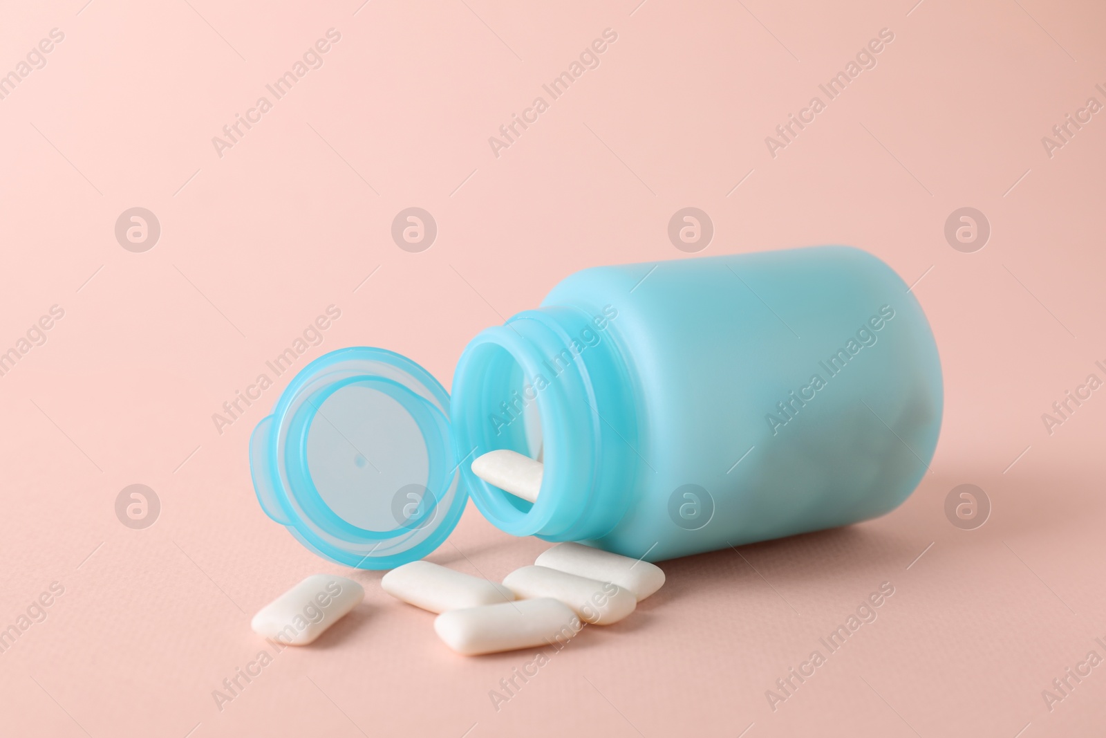 Photo of Jar with chewing gums on light pink background