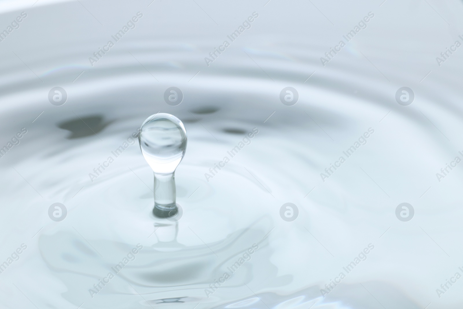 Photo of Splash of clear water with drop on light grey background, closeup