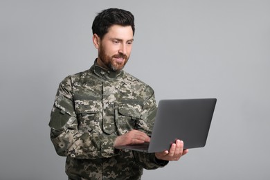 Photo of Soldier using laptop against light grey background. Military service
