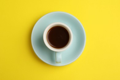 Photo of Tasty coffee in cup on yellow background, top view