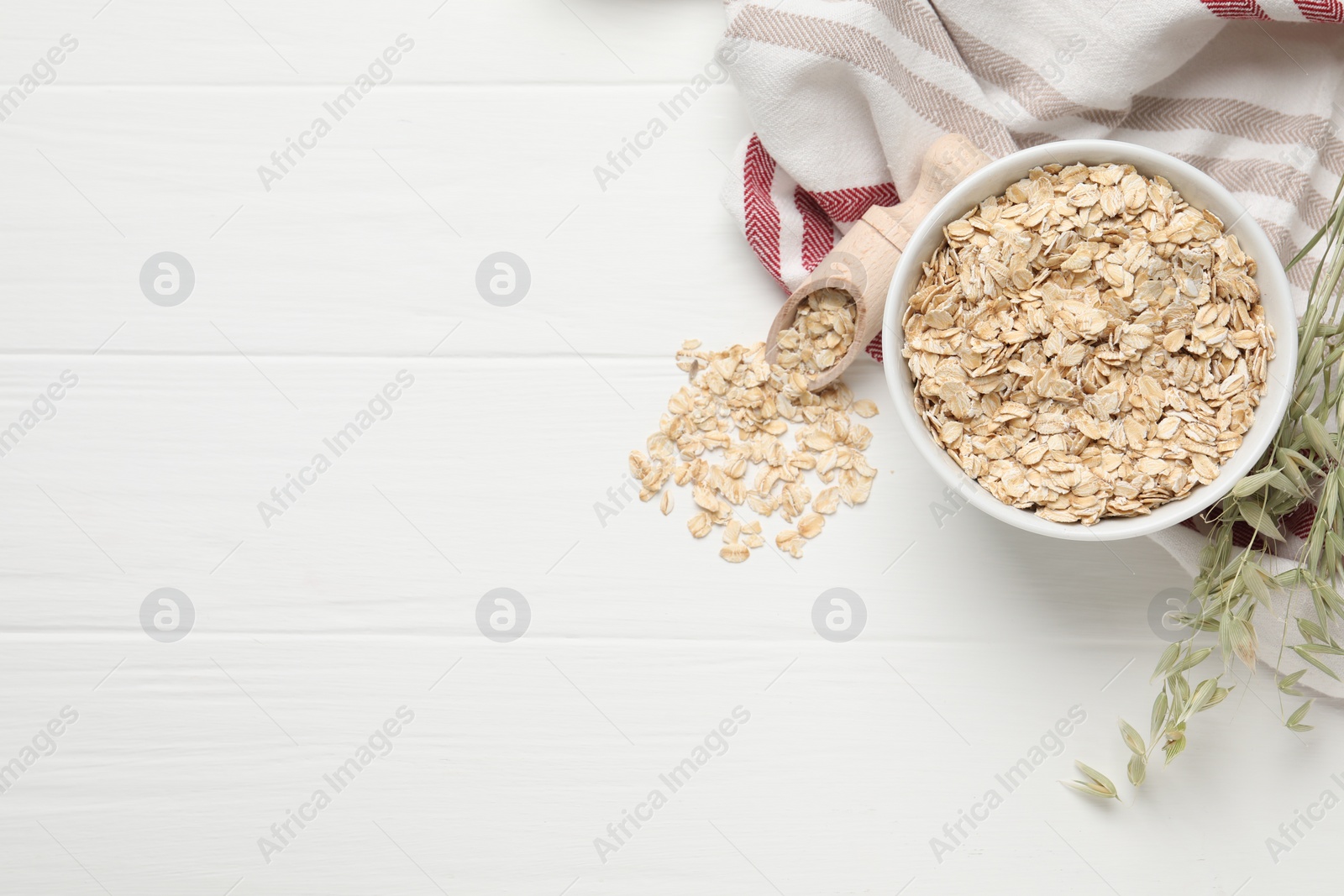 Photo of Oatmeal and branches with florets on white wooden table, flat lay. Space for text