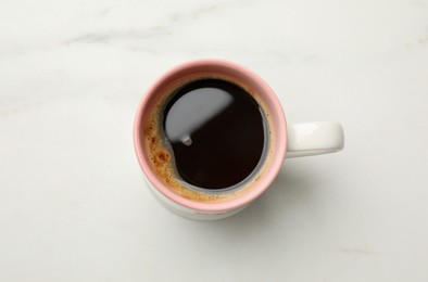 Cup of aromatic coffee on white table, top view