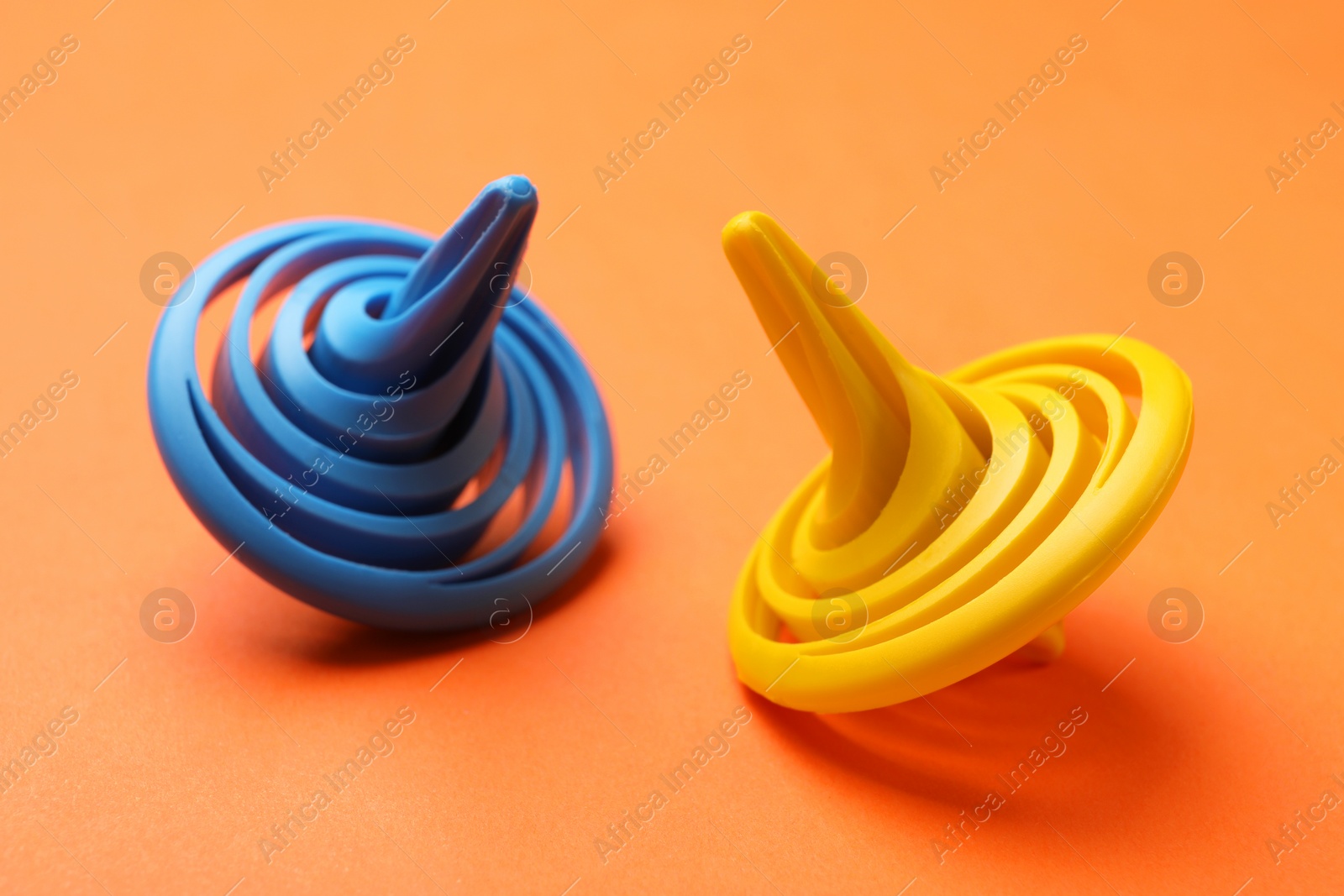 Photo of Blue and yellow spinning tops on orange background, closeup