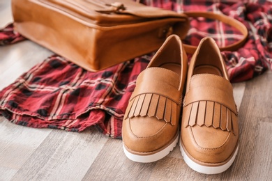 Stylish female shoes, dress and bag on wooden floor