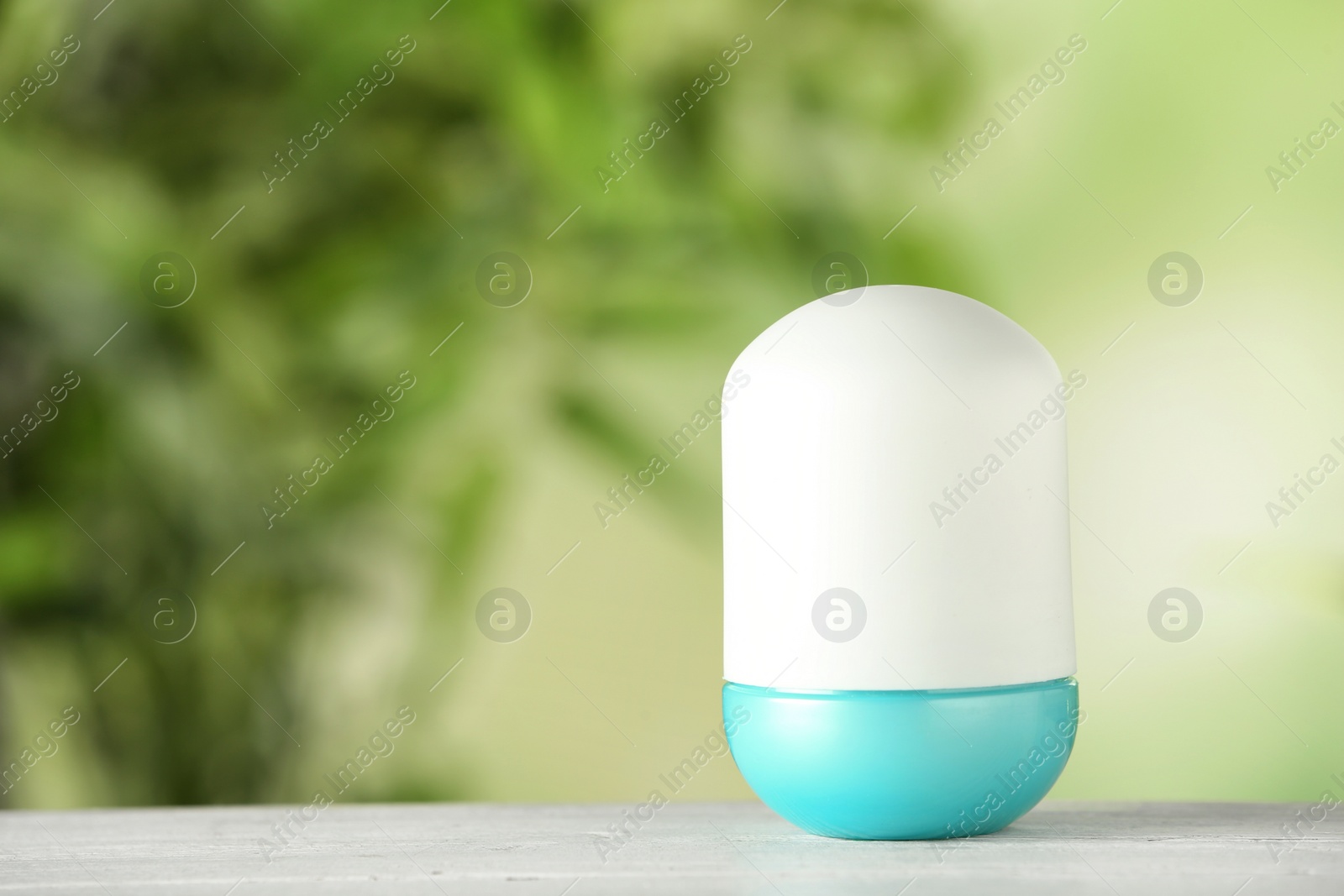 Photo of Deodorant container on white wooden table against blurred background. Space for text