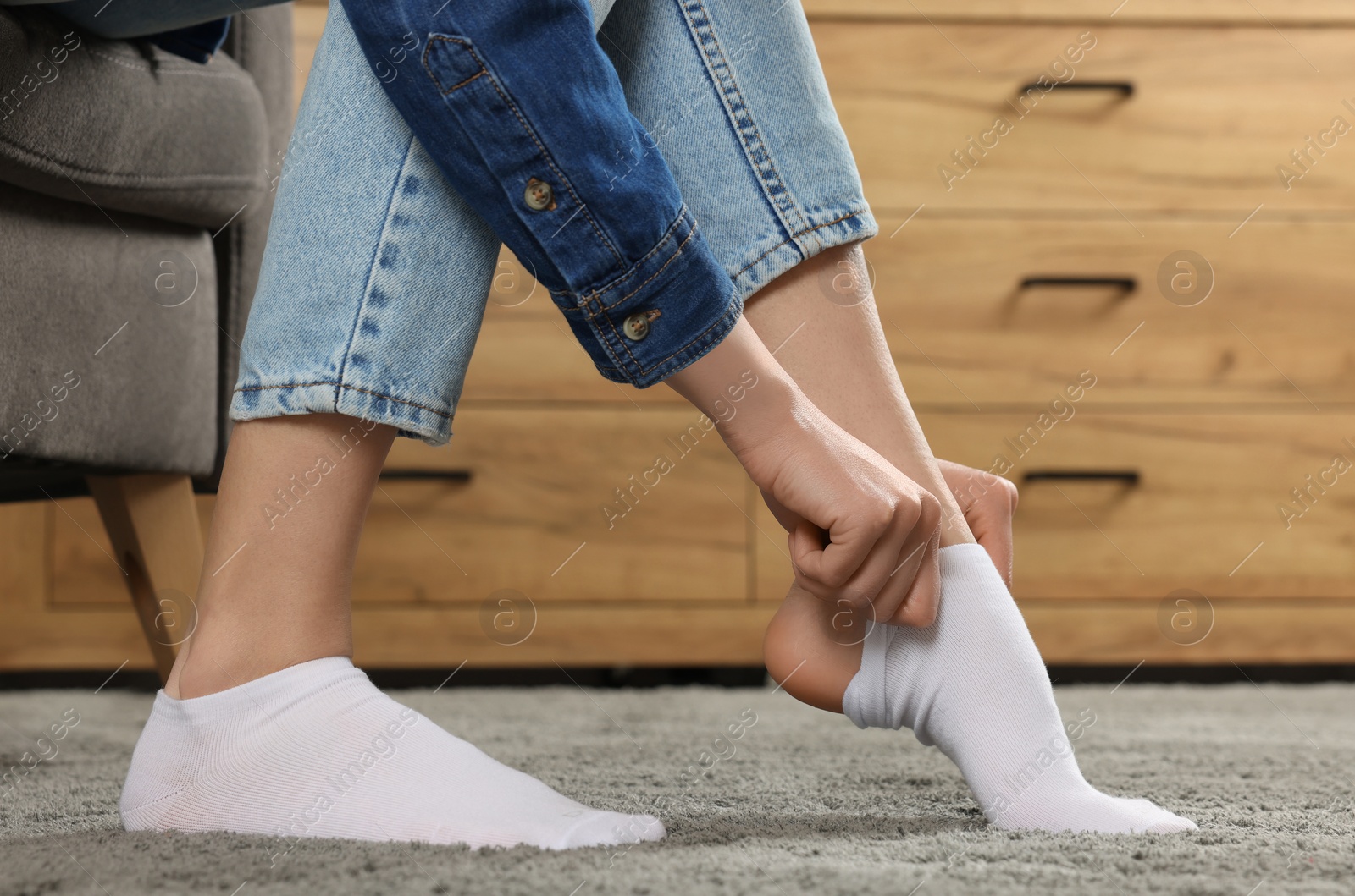 Photo of Woman putting on white socks at home, closeup