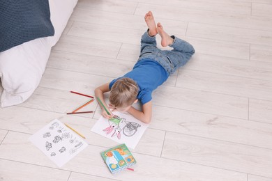 Photo of Little boy coloring on warm floor at home, above view. Heating system