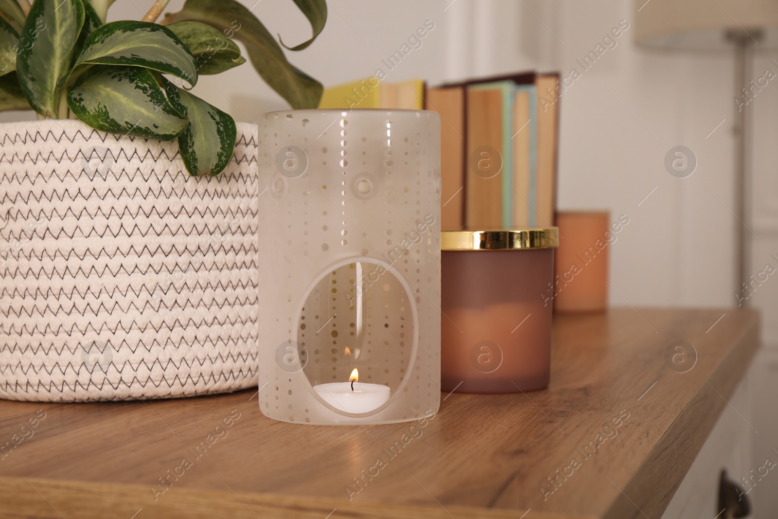 Photo of Stylish aroma lamp with small candle on wooden cabinet indoors