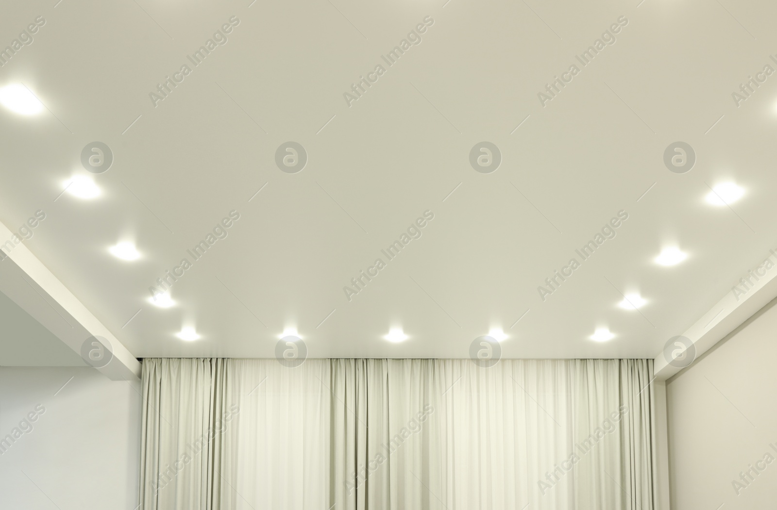 Photo of White stretch ceiling with spot lights in room