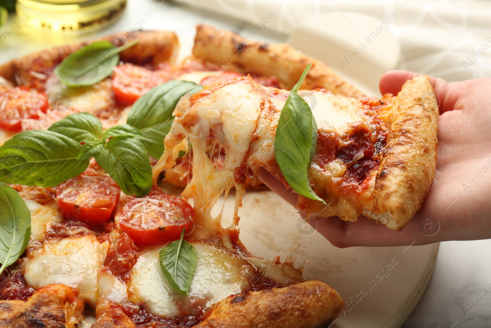 Photo of Woman taking piece of delicious Margherita pizza at table, closeup