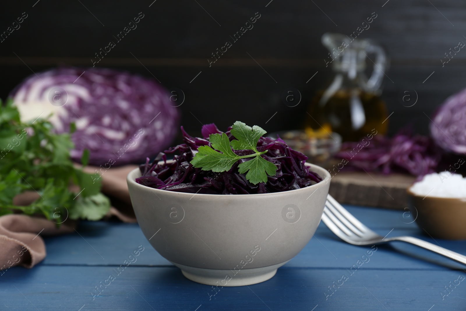 Photo of Tasty red cabbage sauerkraut with parsley on light blue wooden table