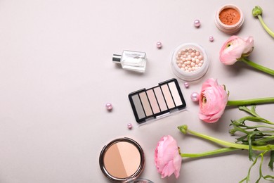 Photo of Flat lay composition with different makeup products and beautiful spring flowers on gray background, space for text