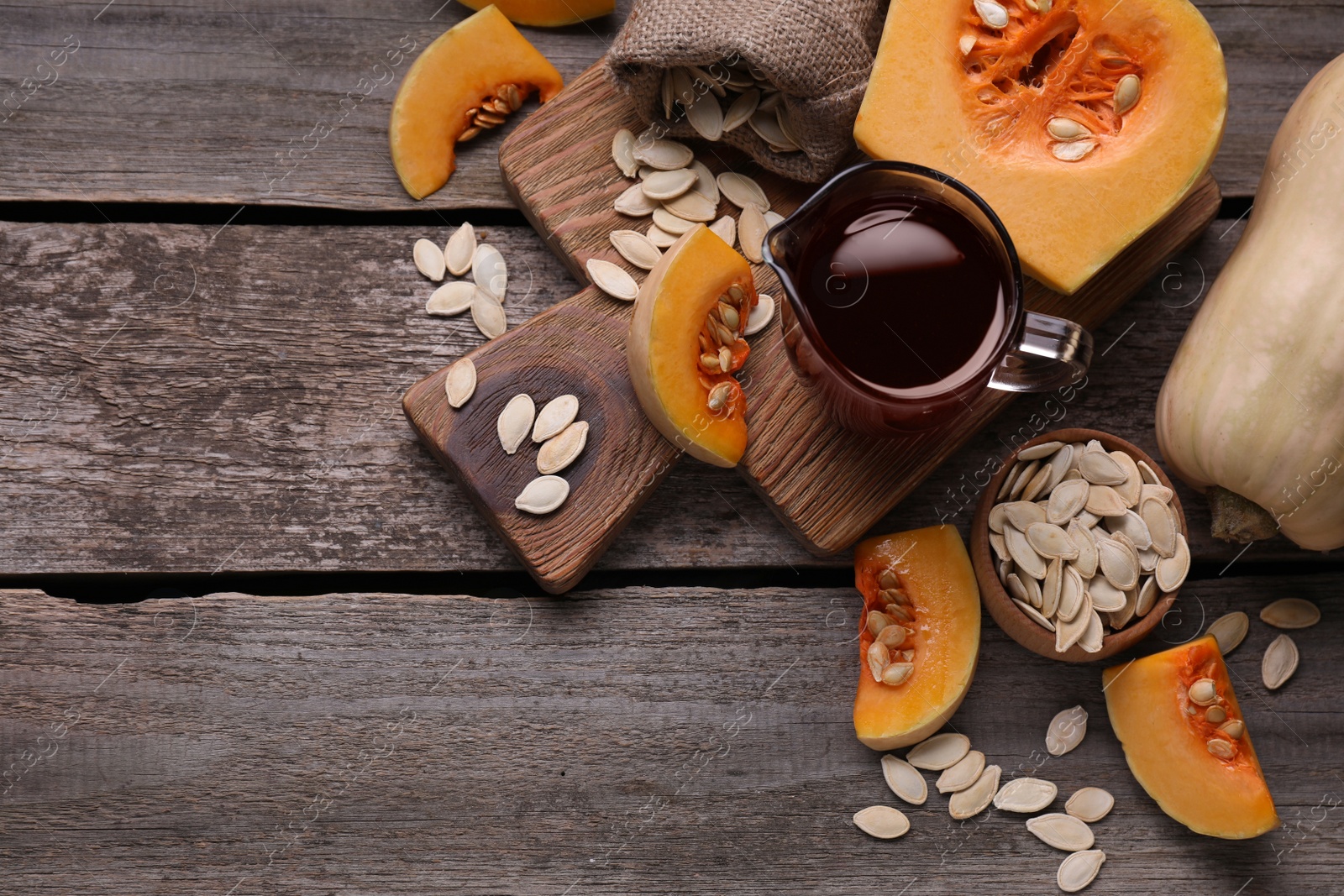 Photo of Flat lay composition with pumpkin seed oil in glass pitcher on wooden table. Space for text