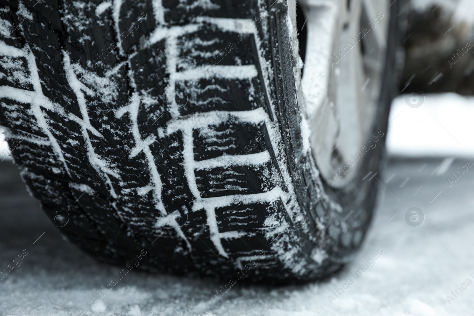 Photo of Modern car with winter tires on snowy road, closeup