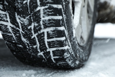 Modern car with winter tires on snowy road, closeup