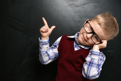 Photo of Funny little child wearing glasses near chalkboard. First time at school