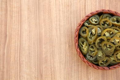 Photo of Pickled green jalapeno peppers on wooden table, top view. Space for text