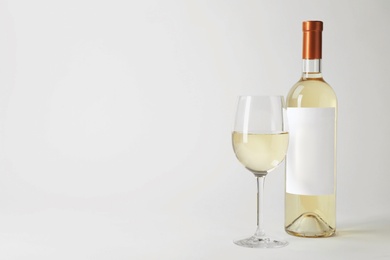 Bottle and glass with delicious wine on white background
