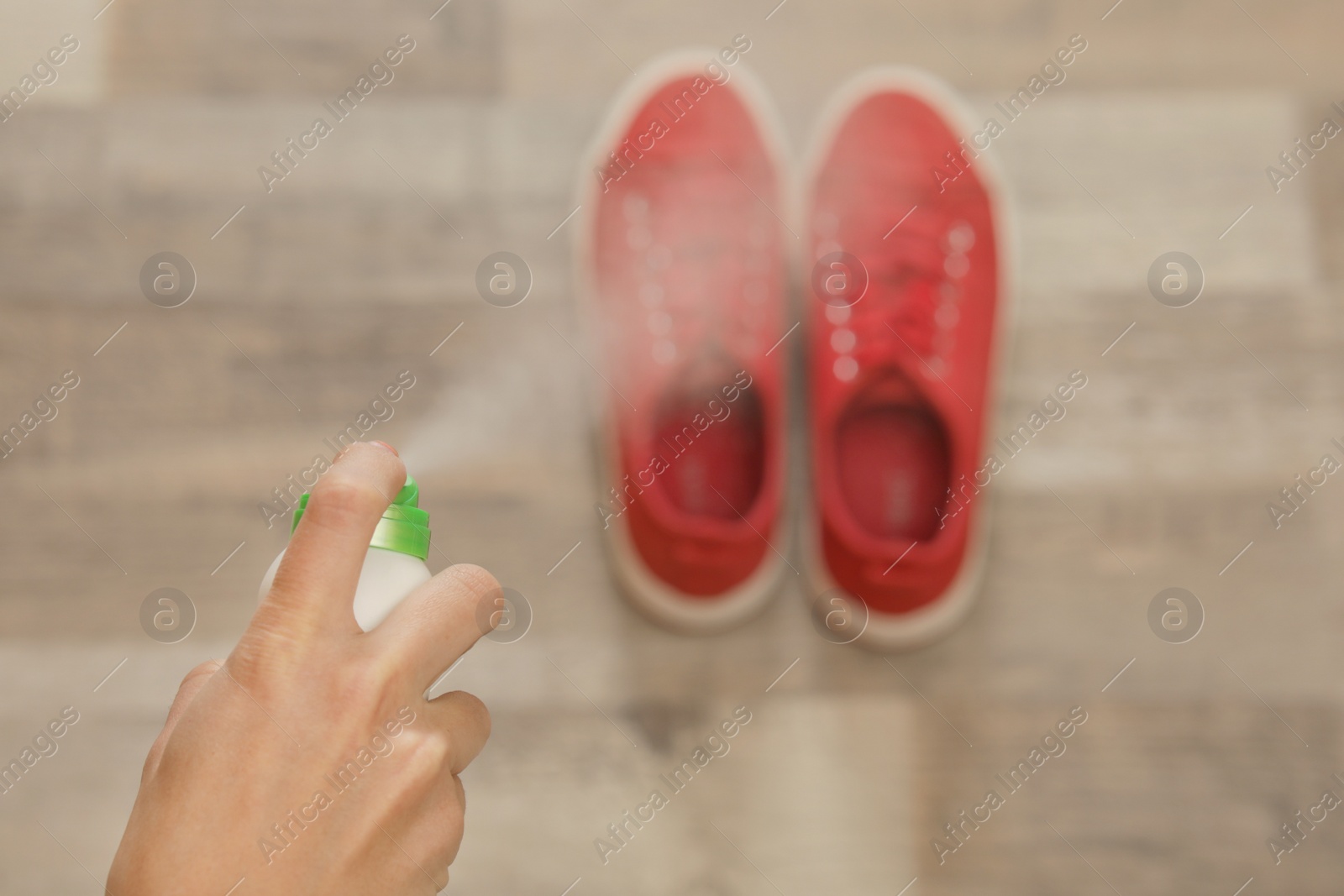 Photo of Woman spraying deodorant over pair of shoes at home, closeup. Space for text