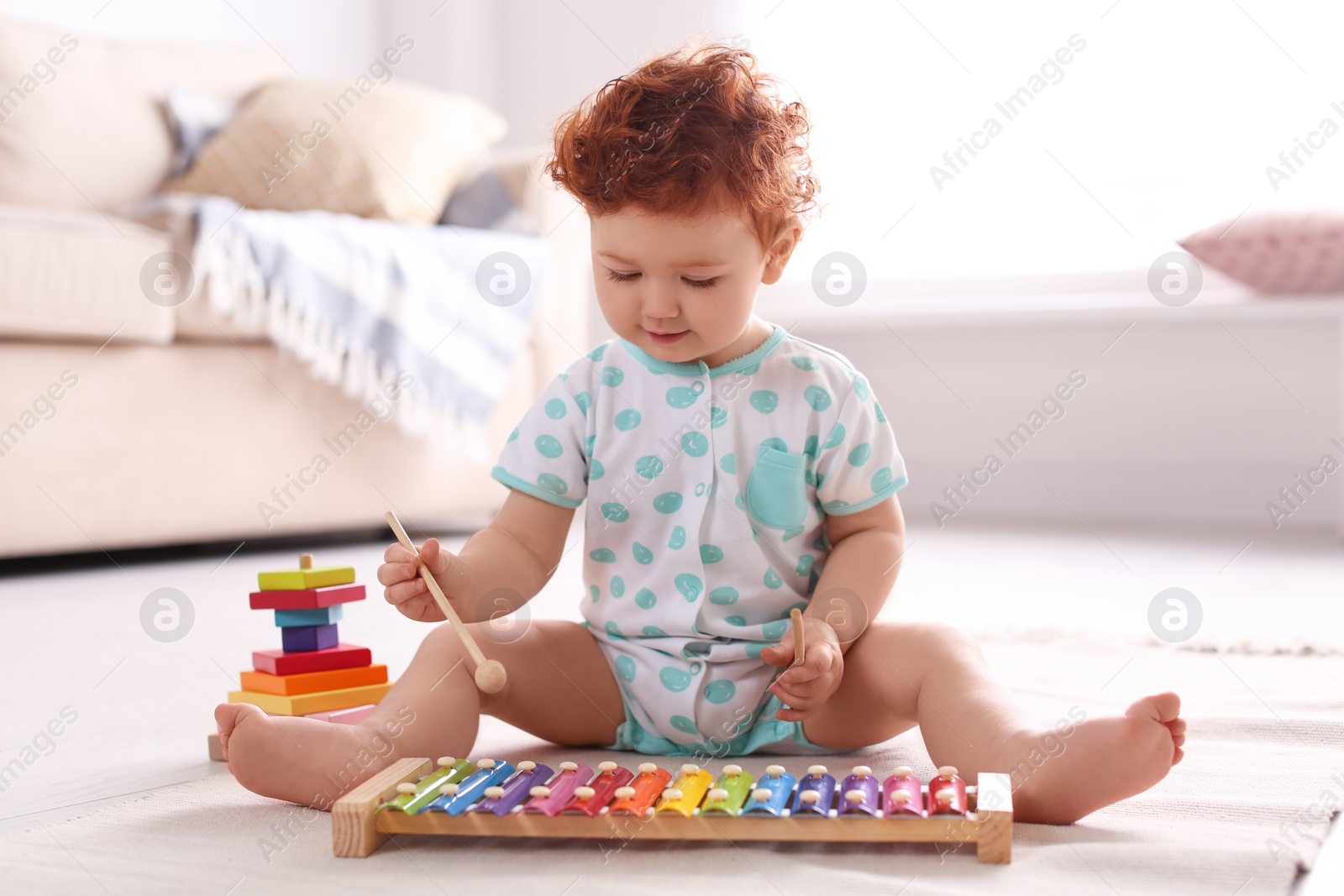 Photo of Cute little child playing with xylophone on floor at home