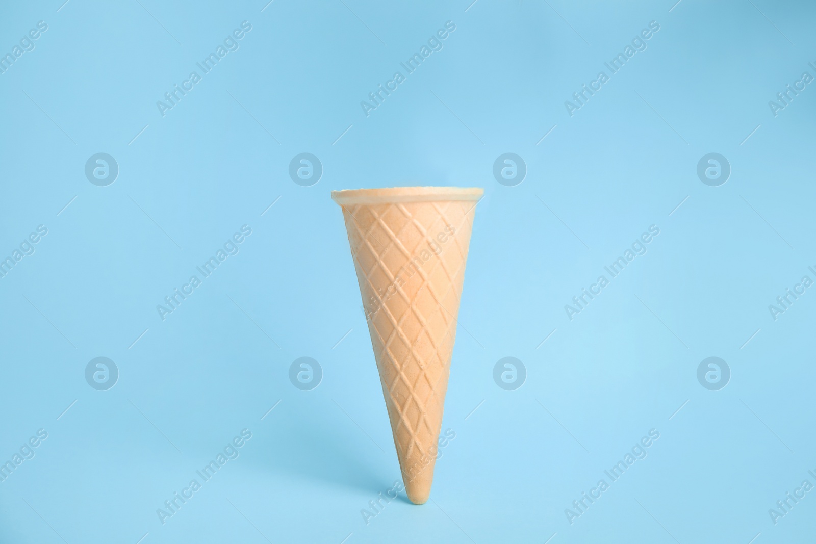 Photo of Empty wafer ice cream cone on blue background