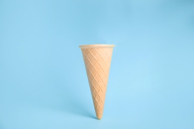 Photo of Empty wafer ice cream cone on blue background