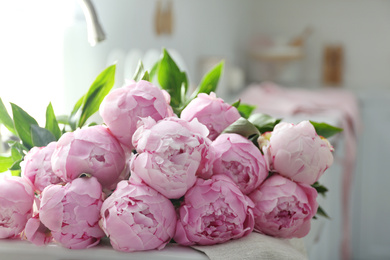 Bouquet of beautiful pink peonies on counter in kitchen