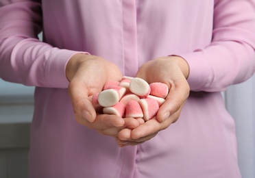 Photo of Young woman holding handful of tasty jelly candies, closeup