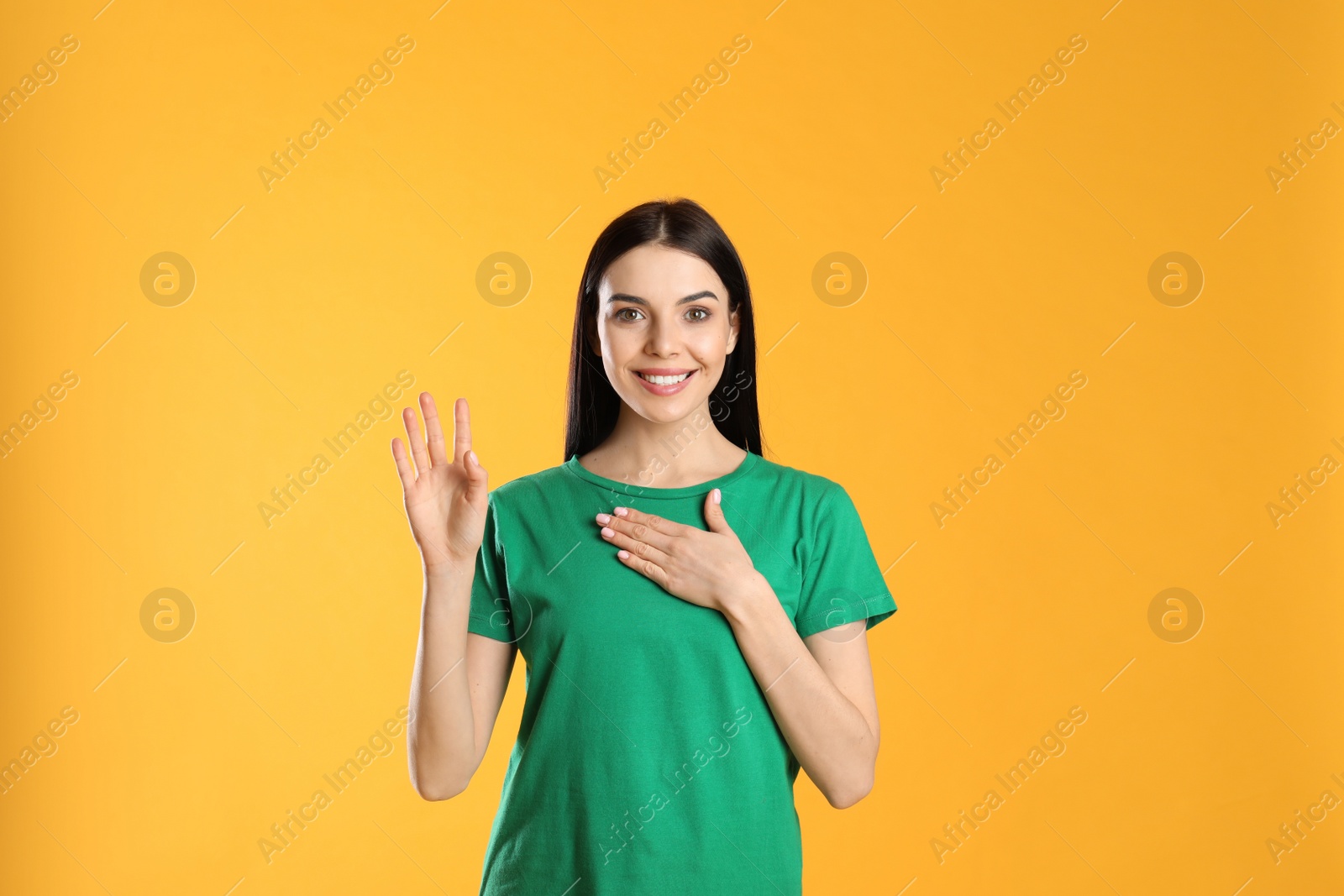 Photo of Attractive young woman showing hello gesture on yellow background