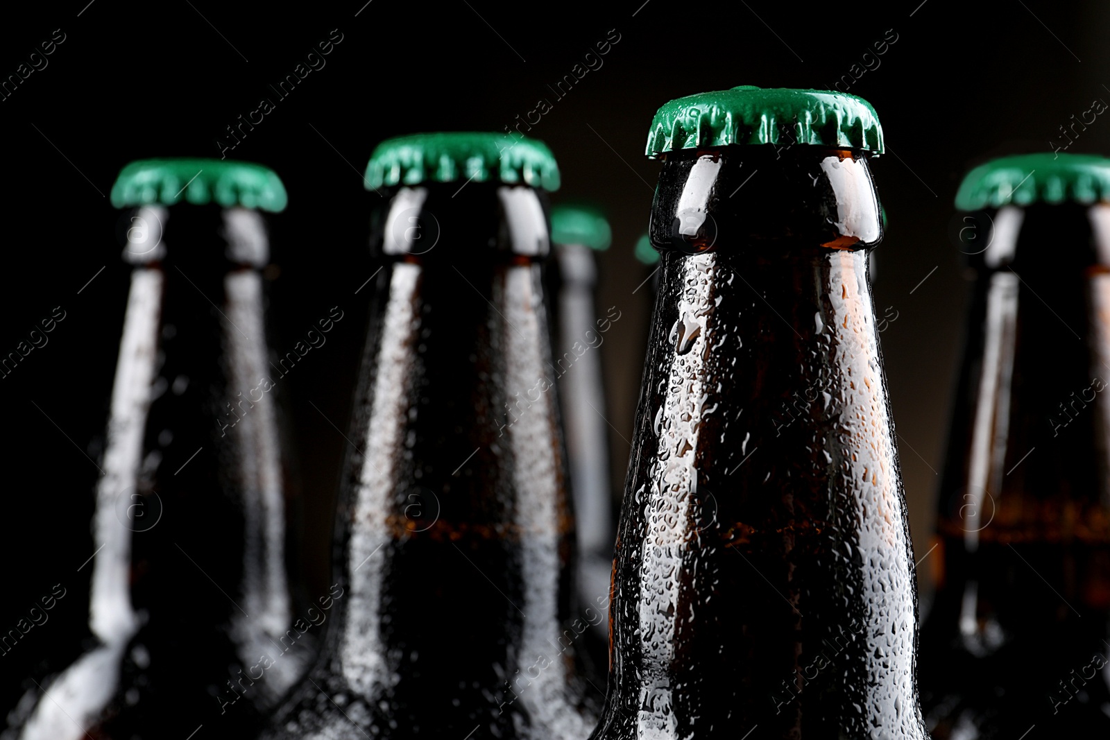 Photo of Many bottles of beer on dark background, closeup