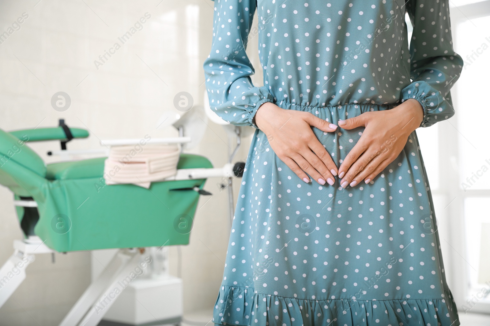 Photo of Gynecological checkup. Woman making heart with hands on her belly in clinic, closeup. Space for text