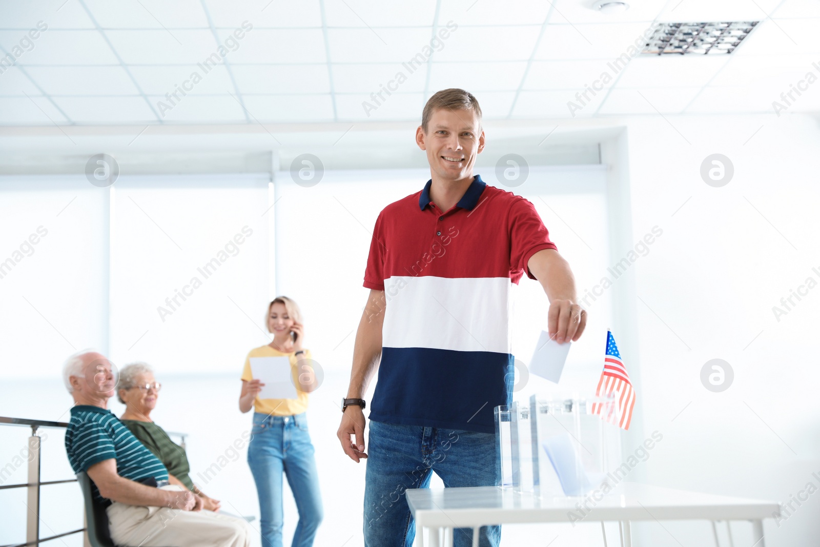 Photo of Man putting ballot paper into box at polling station