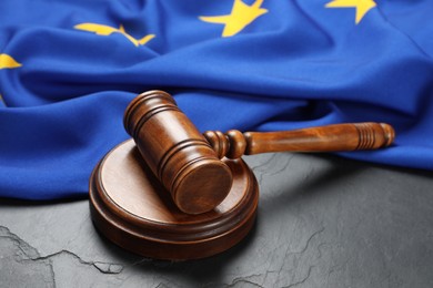 Wooden judge's gavel and flag of European Union on black table