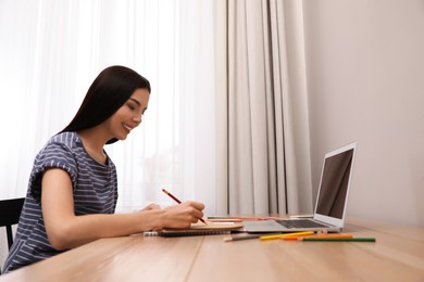 Photo of Happy woman drawing picture at online art lesson indoors. Distant learning