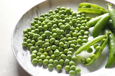 Photo of Plate with green peas on light background, closeup