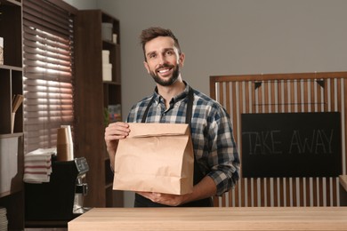 Photo of Worker with paper bag at counter in cafe