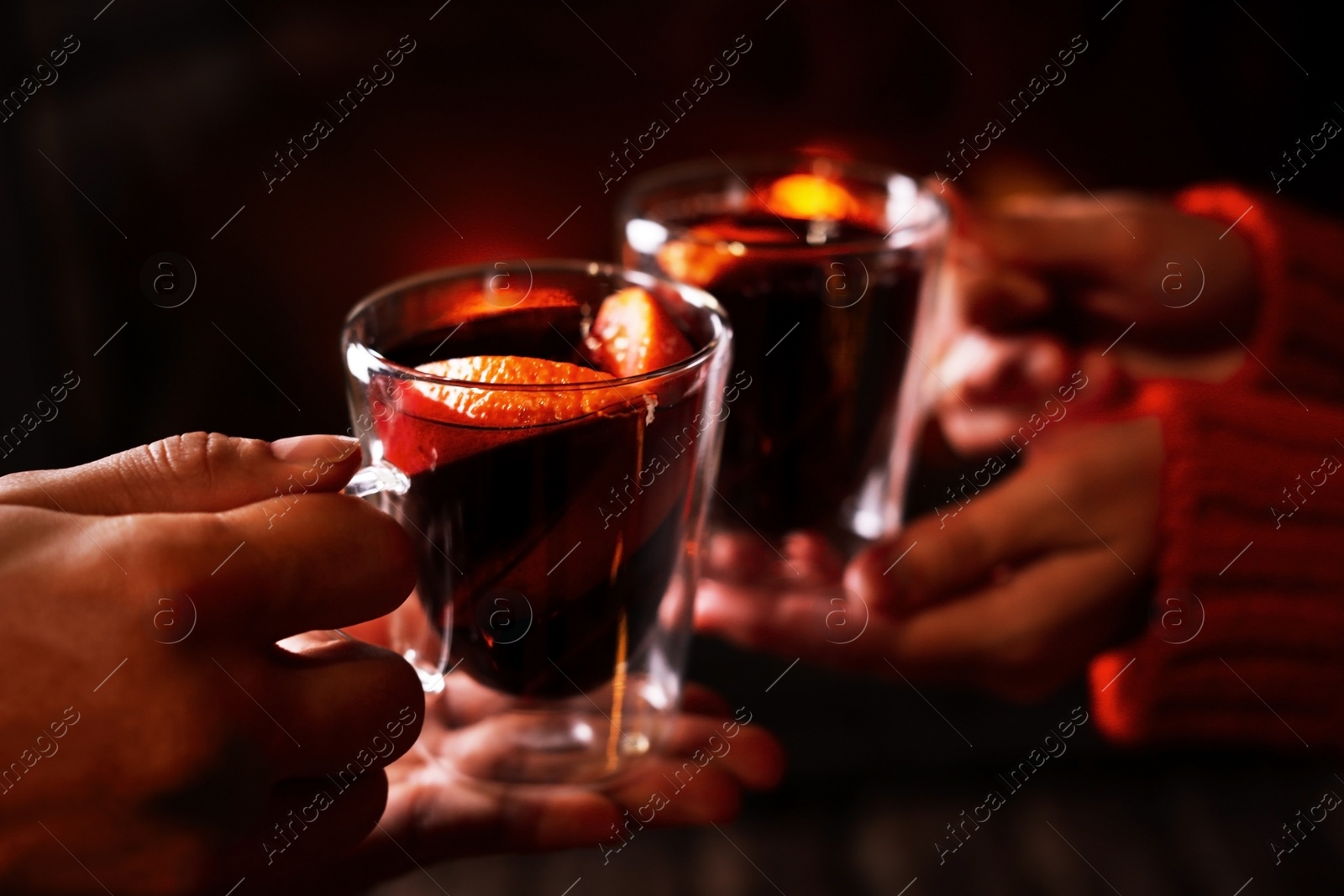 Photo of Couple with tasty mulled wine near fireplace indoors, closeup