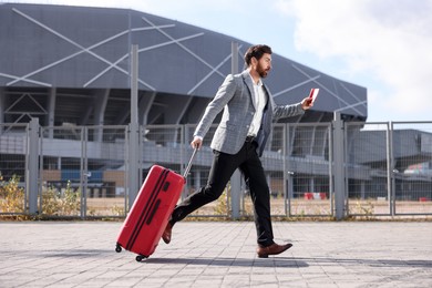 Being late. Businessman with red suitcase and passport running outdoors