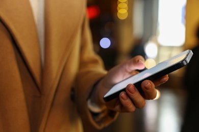 Woman using smartphone on night city street, closeup