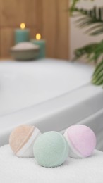 Photo of Colorful bath bombs on white towel in bathroom