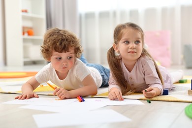 Photo of Cute little children drawing on floor in kindergarten