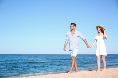 Photo of Lovely couple walking on beach. Space for text